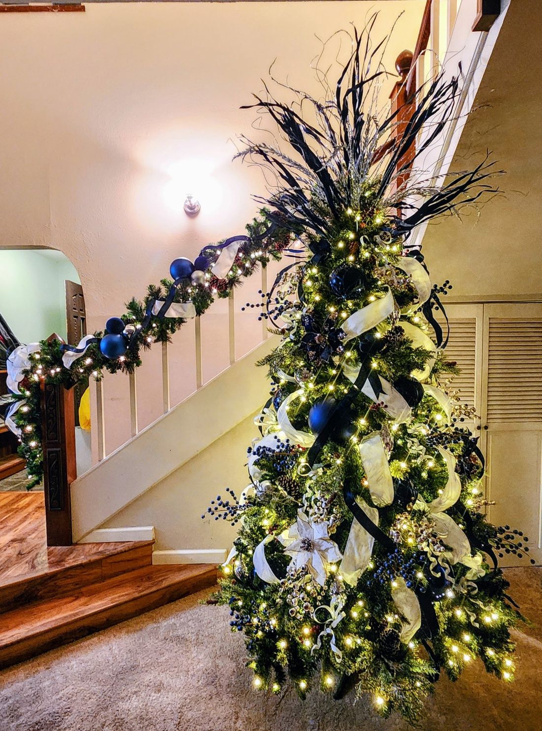 Navy and ivory tree beside a staircase garland with matching navy ornaments