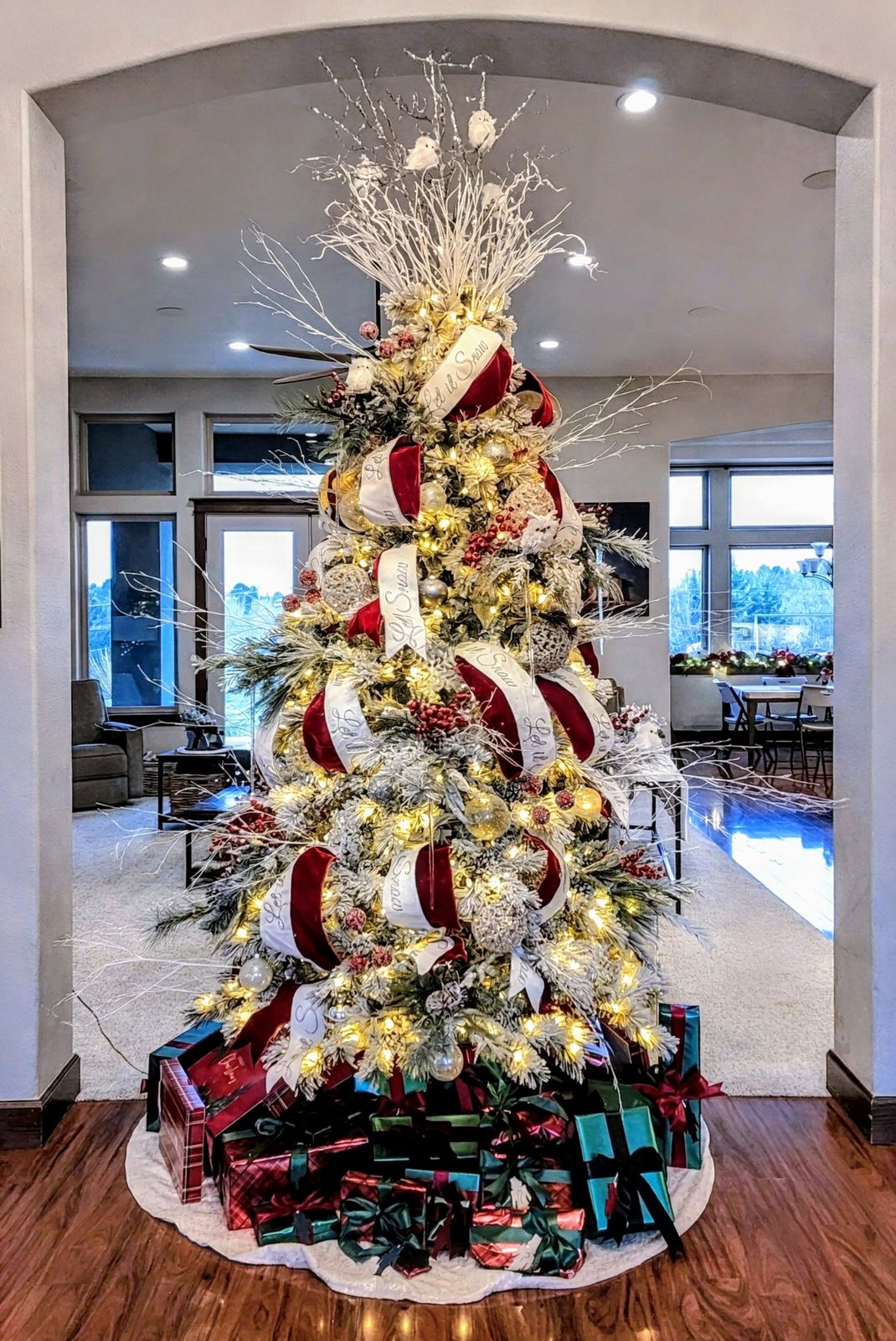 Flocked tree with red and white ribbon, white branches and snowy owls framed by an archway